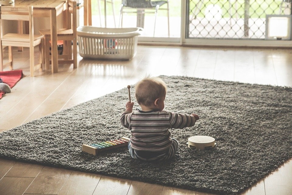 Малыш сидит на ковре и играет на музыкальных инструментах