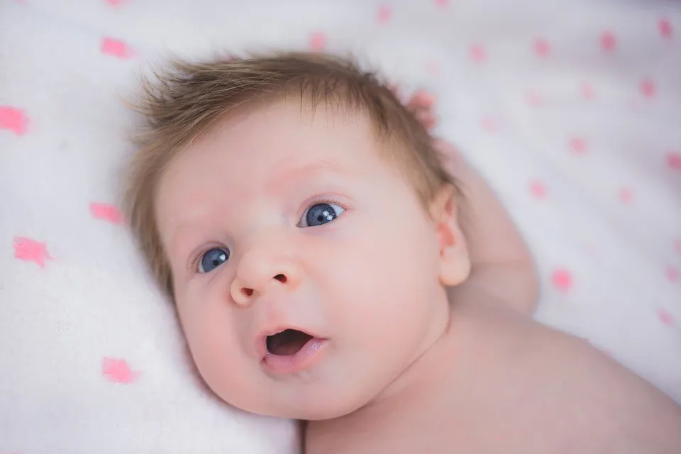 Новорожденный с голубыми глазами лежит на пеленке